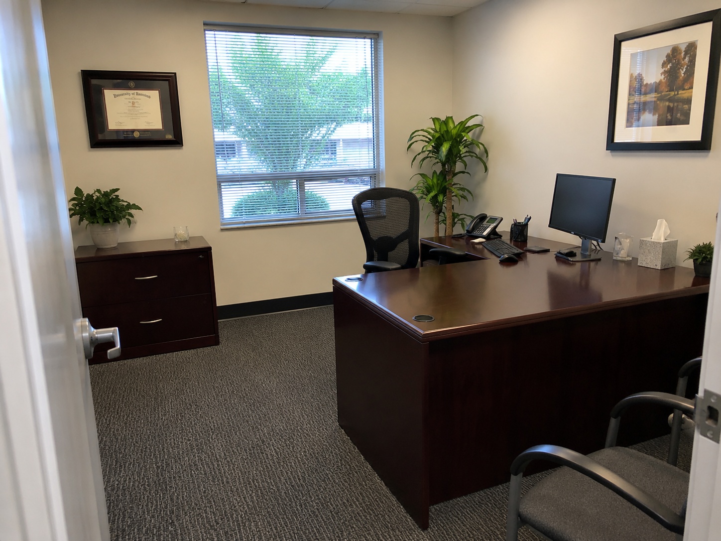 Clean professional office with desk, computer and seating