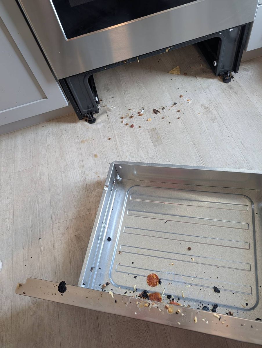 Range before cleaning — pulled out with debris behind it